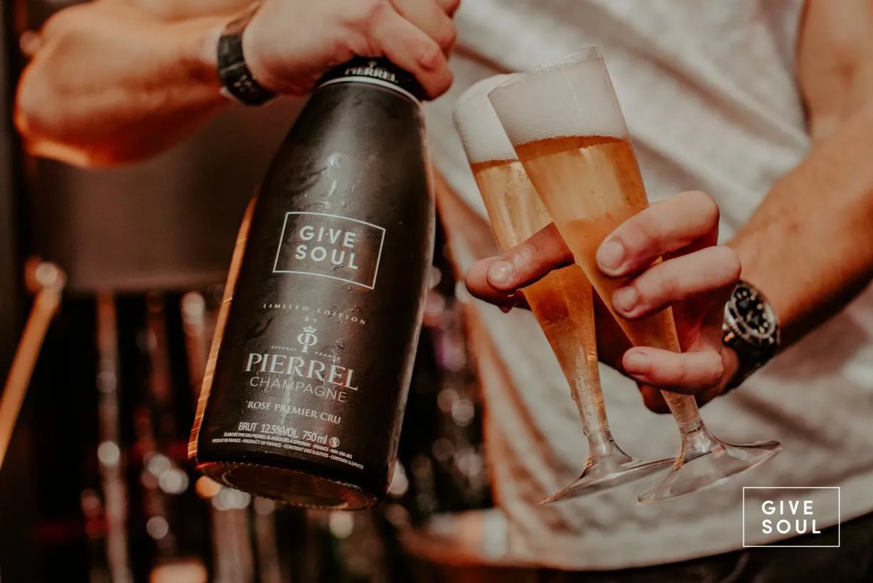 Serveur qui sert une bouteille de Champagne Pierrel personnalisé à bonne température dans deux coupes